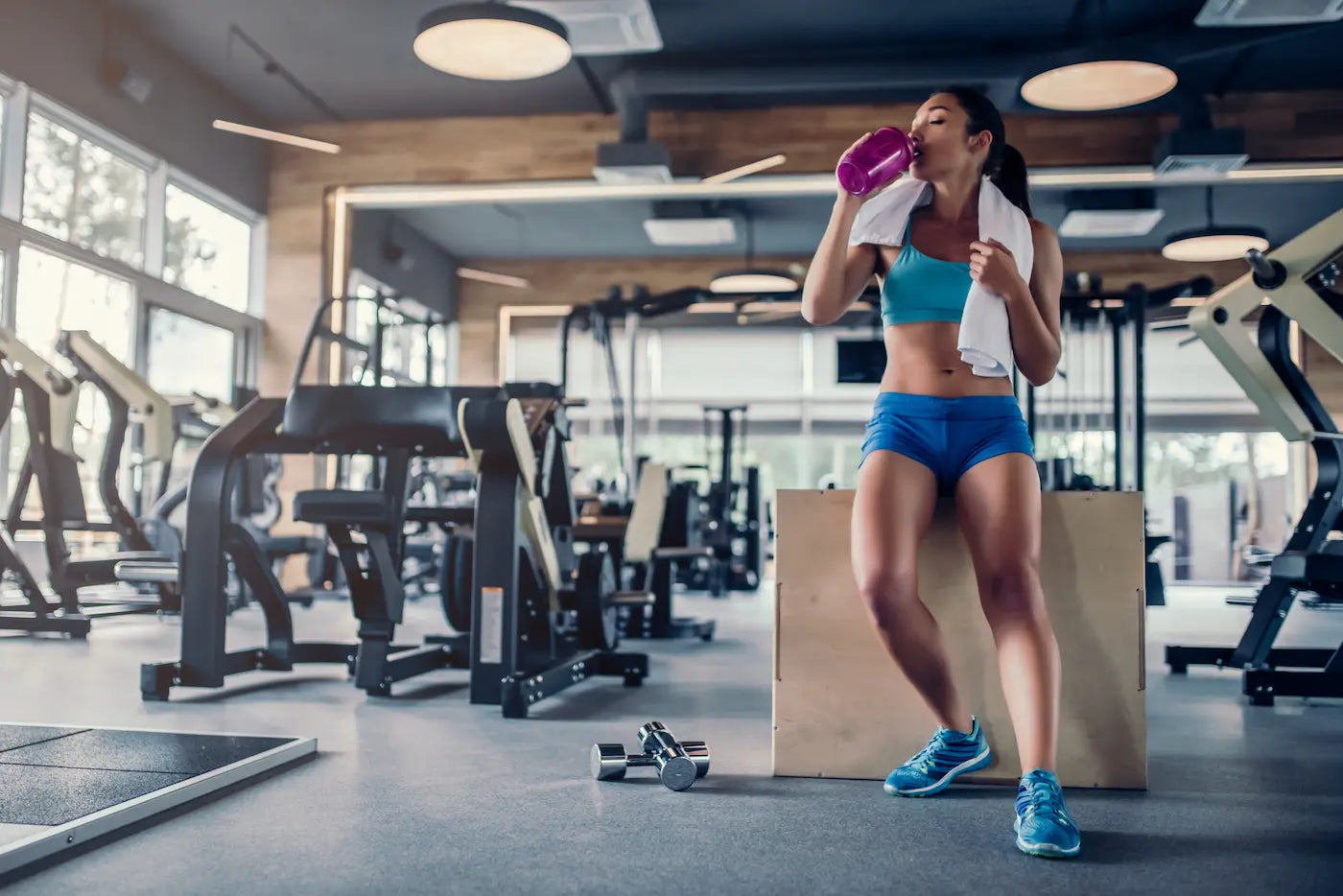 A woman drinking the best preworkout for women at the gym